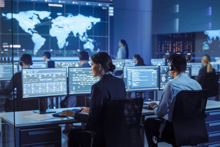 Image of people working on computer in control center.