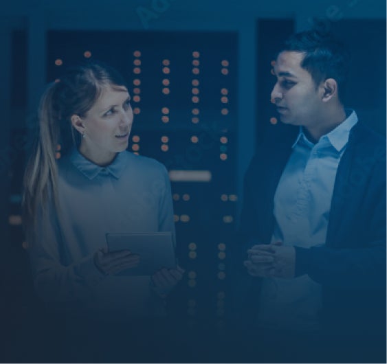 Image of man and woman with tablet in hand having a discussion in a server room.