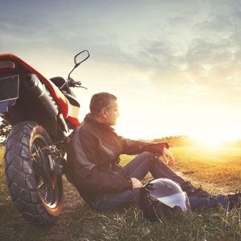 A motorcyclist watches the sun set.