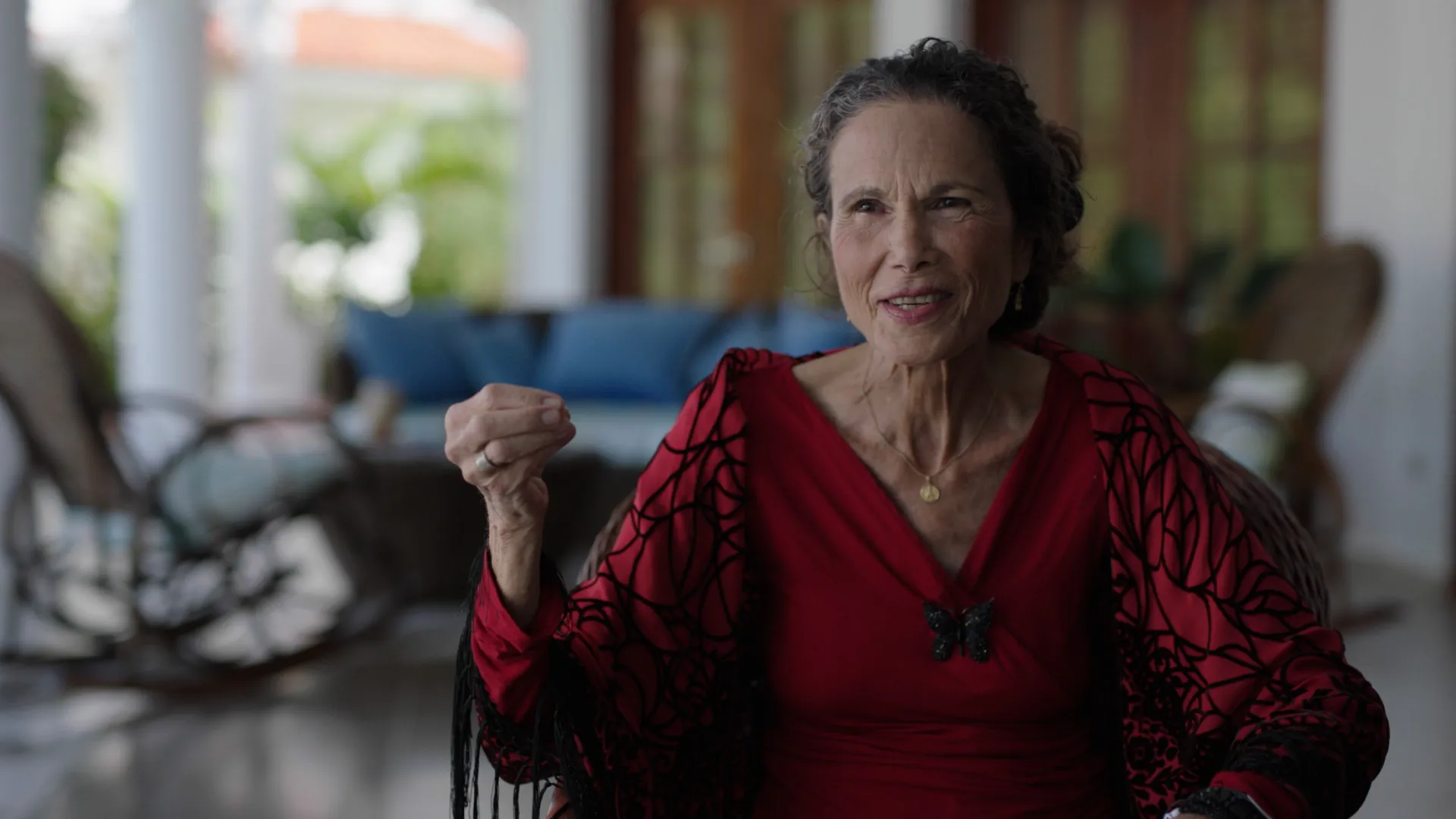 Older woman in red dress speaking to the camera