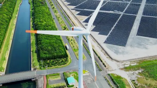 Arial shot of a wind turbine with a large solar farm in the background.