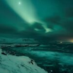 A stunning aurora borealis lighting up the night sky over a snowy landscape.