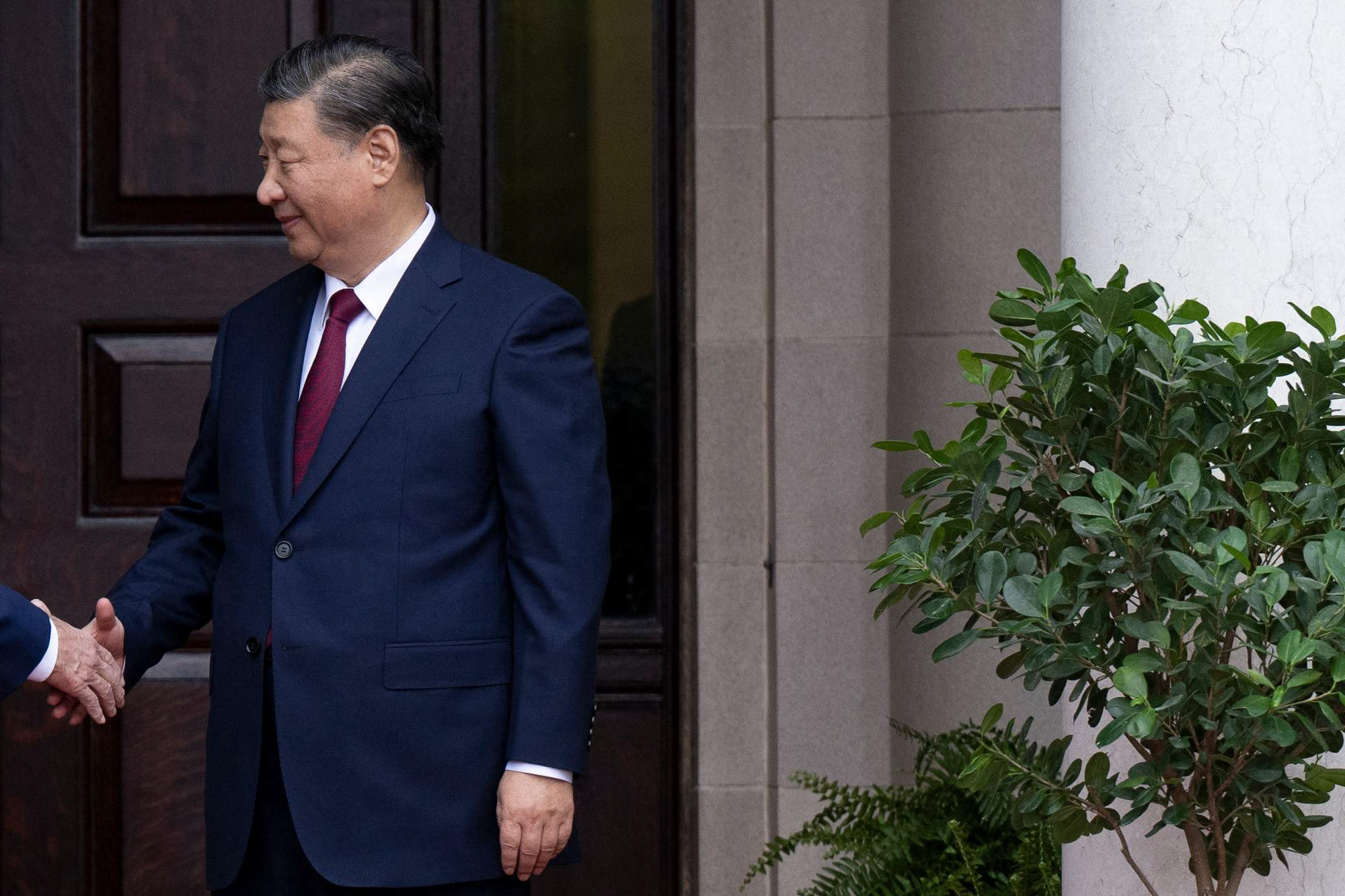 Chinese President Xi Jinping shaking a person's hand.
