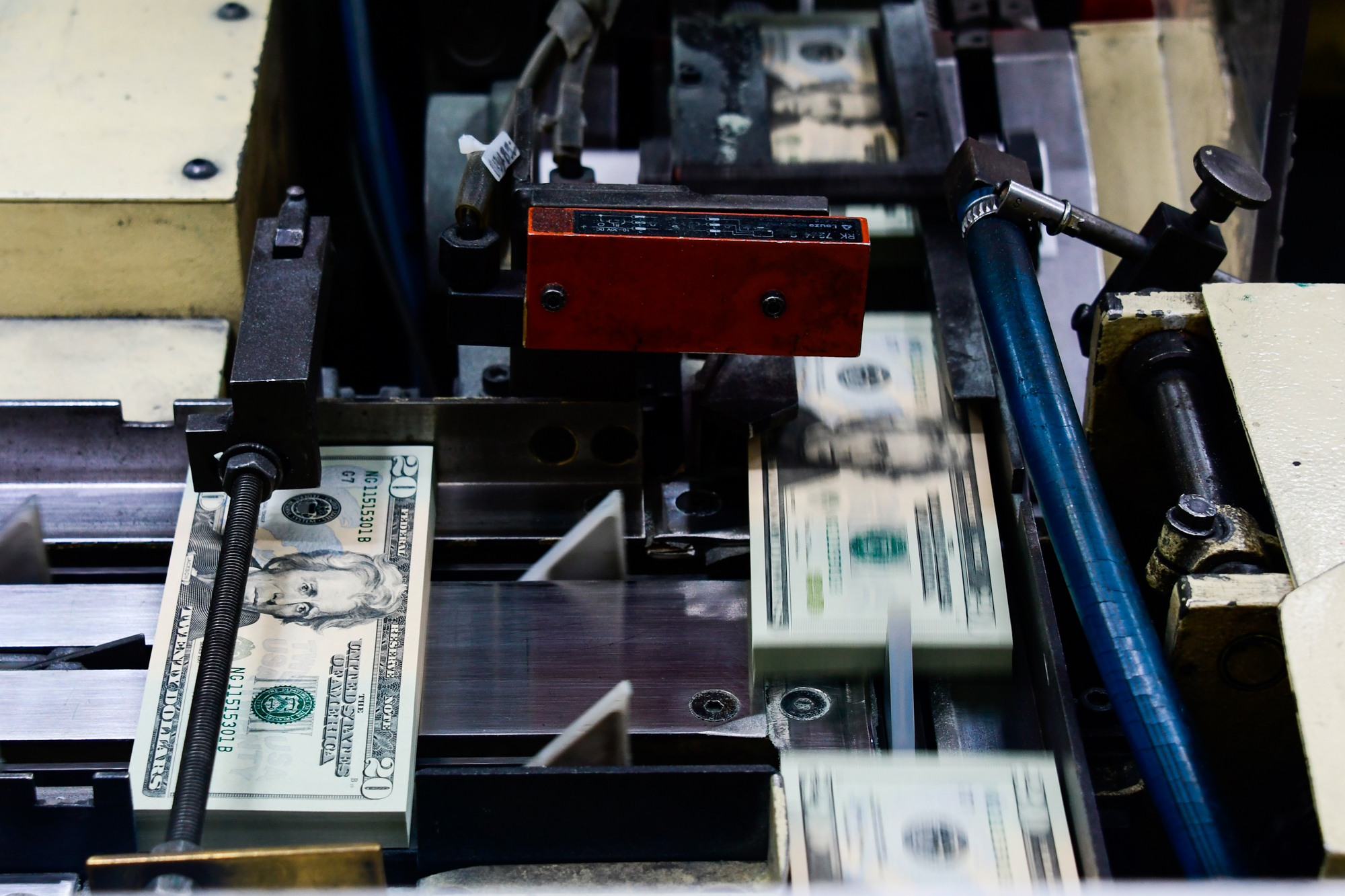 Packs of freshly printed 20 U.S. dollar notes are processed for bundling.