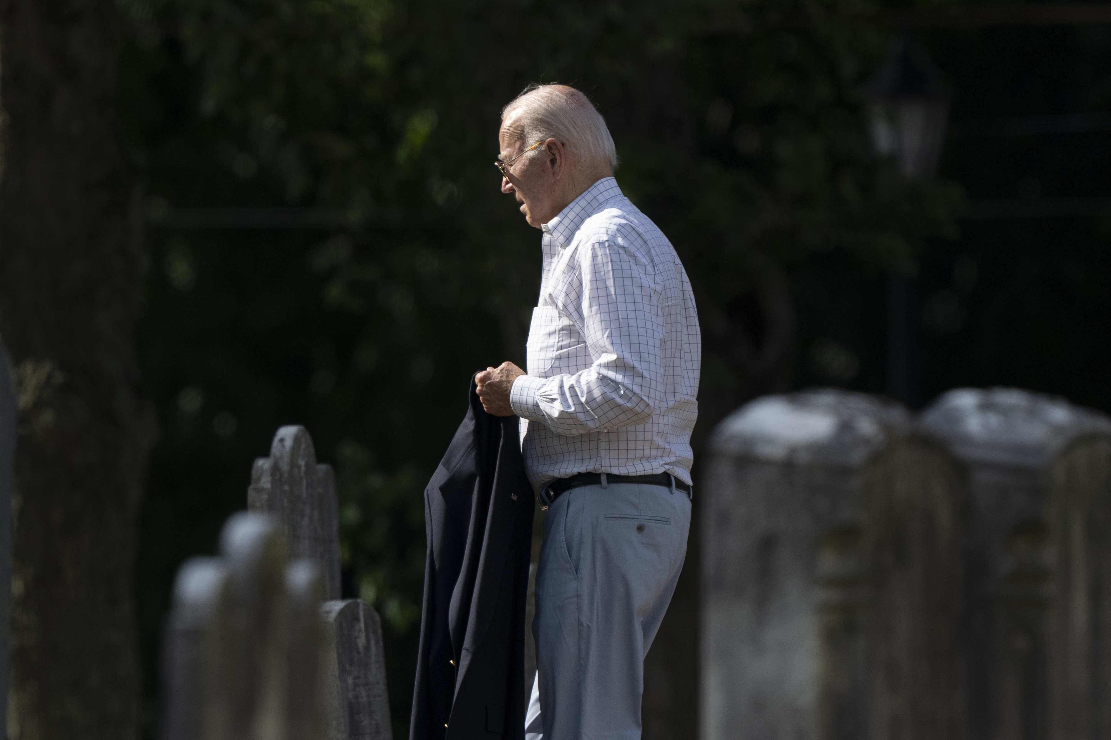 President Joe Biden walks between tombstones as he arrives to attend a mass.