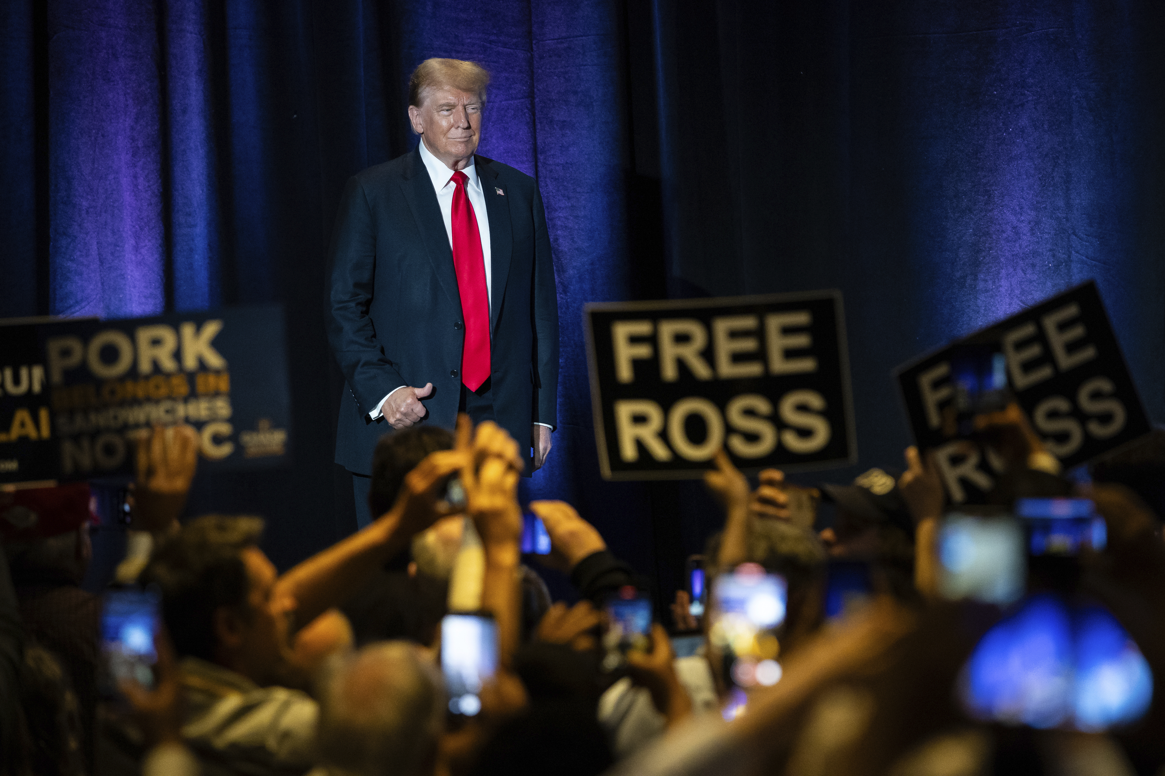 Donald Trump walks on stage as crowd holds signs reading FREE ROSS.