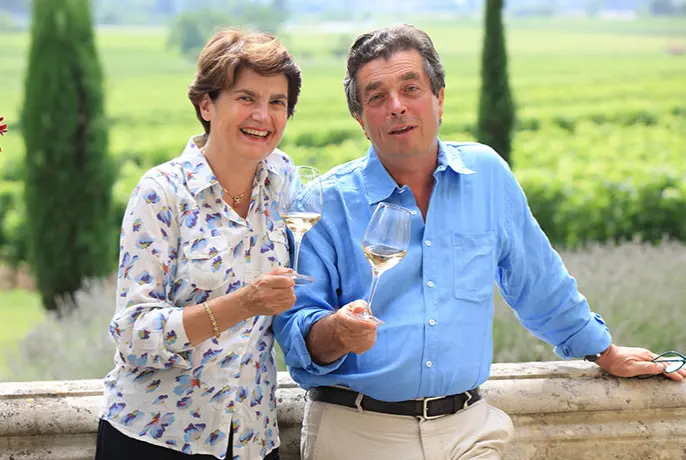 Homem segurando uma caixa com cachos de uva e uma paisagem montanhosa atrás.