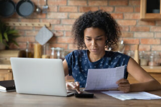 photo - Woman Paying Bills at Kitchen Table