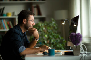 photo - man using computer at desk in home office