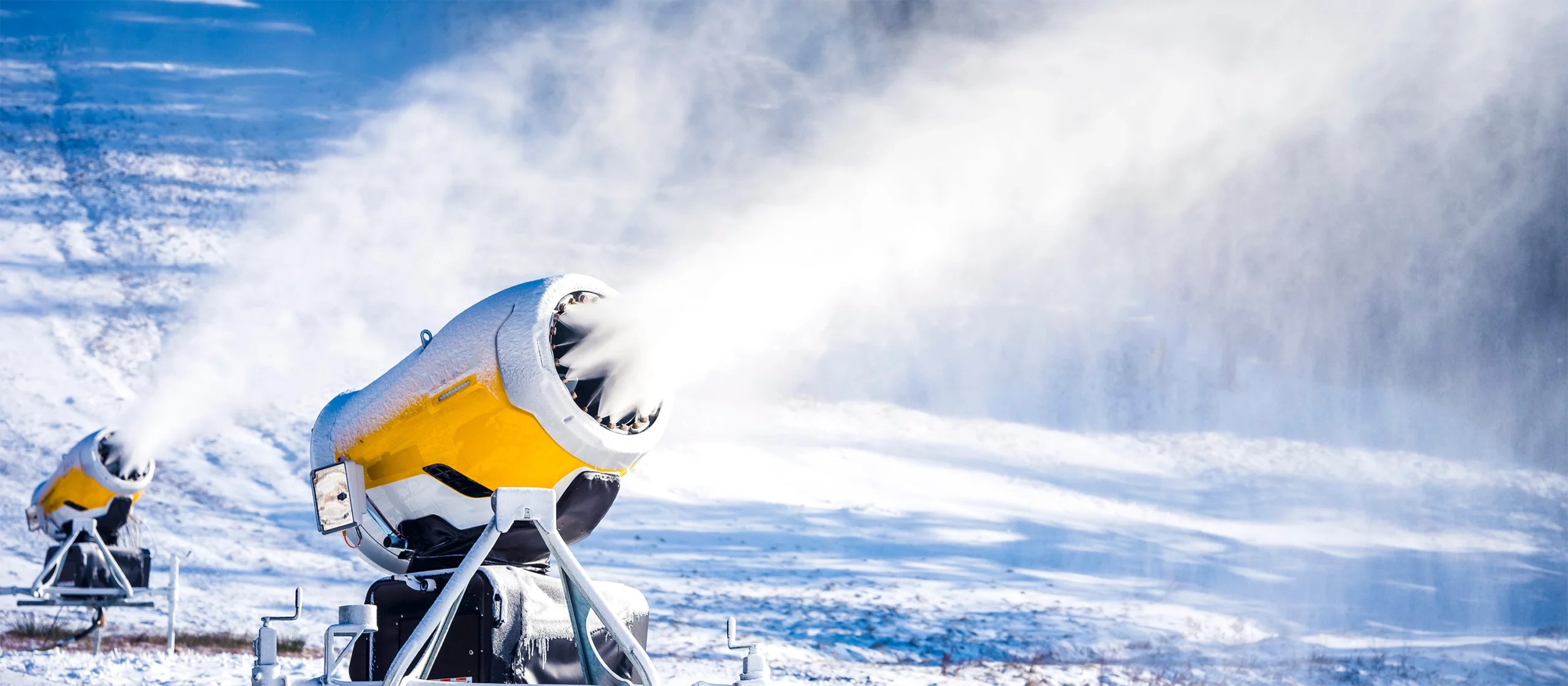 A snow gun sprays water into the air amid a snowy scene.