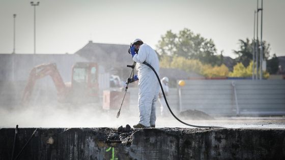 Un ouvrier portant une combinaison de protection nettoie une dalle de béton à l'usine Lubrizol de Rouen le 18 septembre 2020.