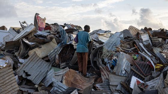 A Mamoudzou, deux semaines après le passage du cyclone Chido, un homme cherche parmi les débris de quoi reconstruire sa maison.