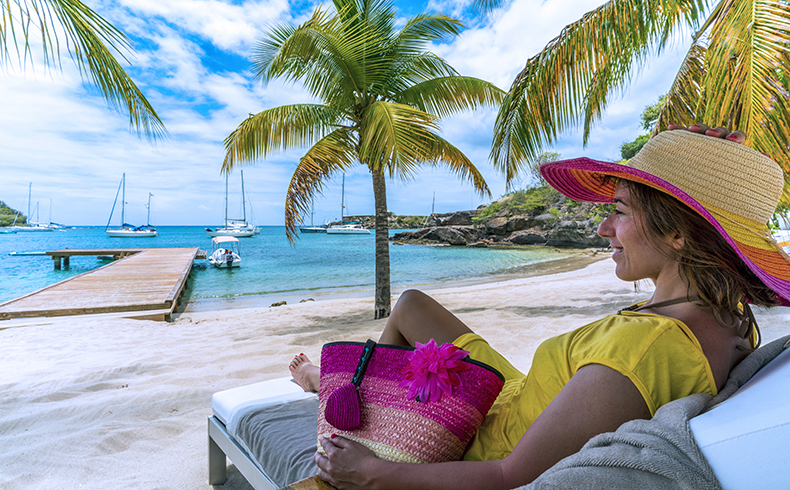 A woman in a sun hat sitting on a beach chair overlooking the water