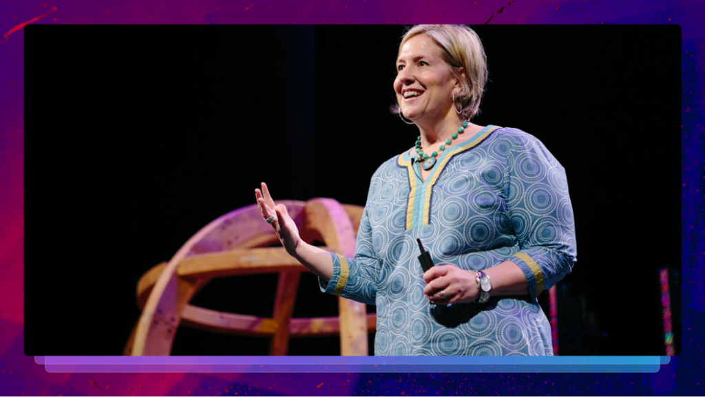 Brené Brown speaking on stage, gesturing with her hand and smiling.