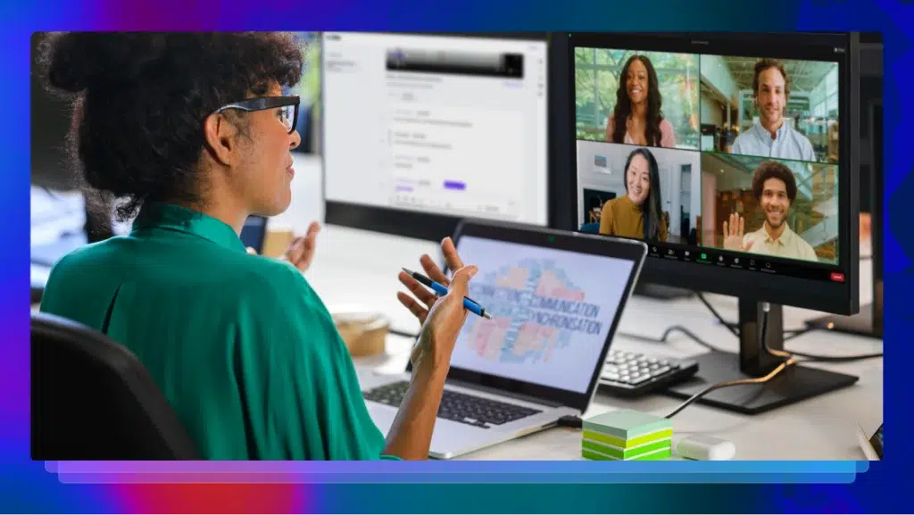 A woman gestures while on a conference call, with a transcription of the call on another screen and a laptop in front of her.