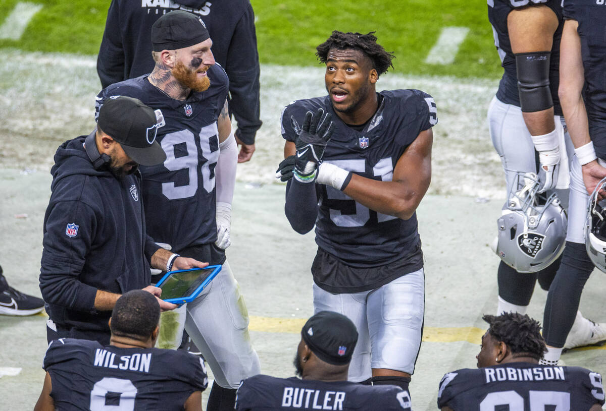 Raiders defensive end Malcolm Koonce (51) retells a play to defensive end Maxx Crosby (98) and ...