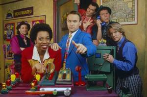 WHERE IN THE WORLD IS CARMEN SANDIEGO, from far left:  Elliott Kerman, Lynne Thigpen, Greg Lee, Sean Altman, Barry Carl, Scott Leonard, 1991-1996.  ph: Frank Capri / ©PBS / Courtesy Everett Collection