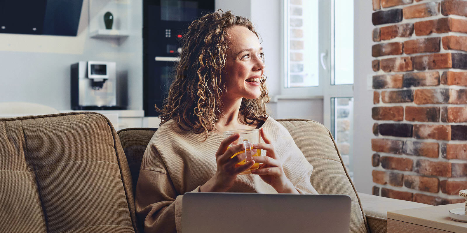 A woman holding a cup of tea and smiling after learning to invest in precious metals