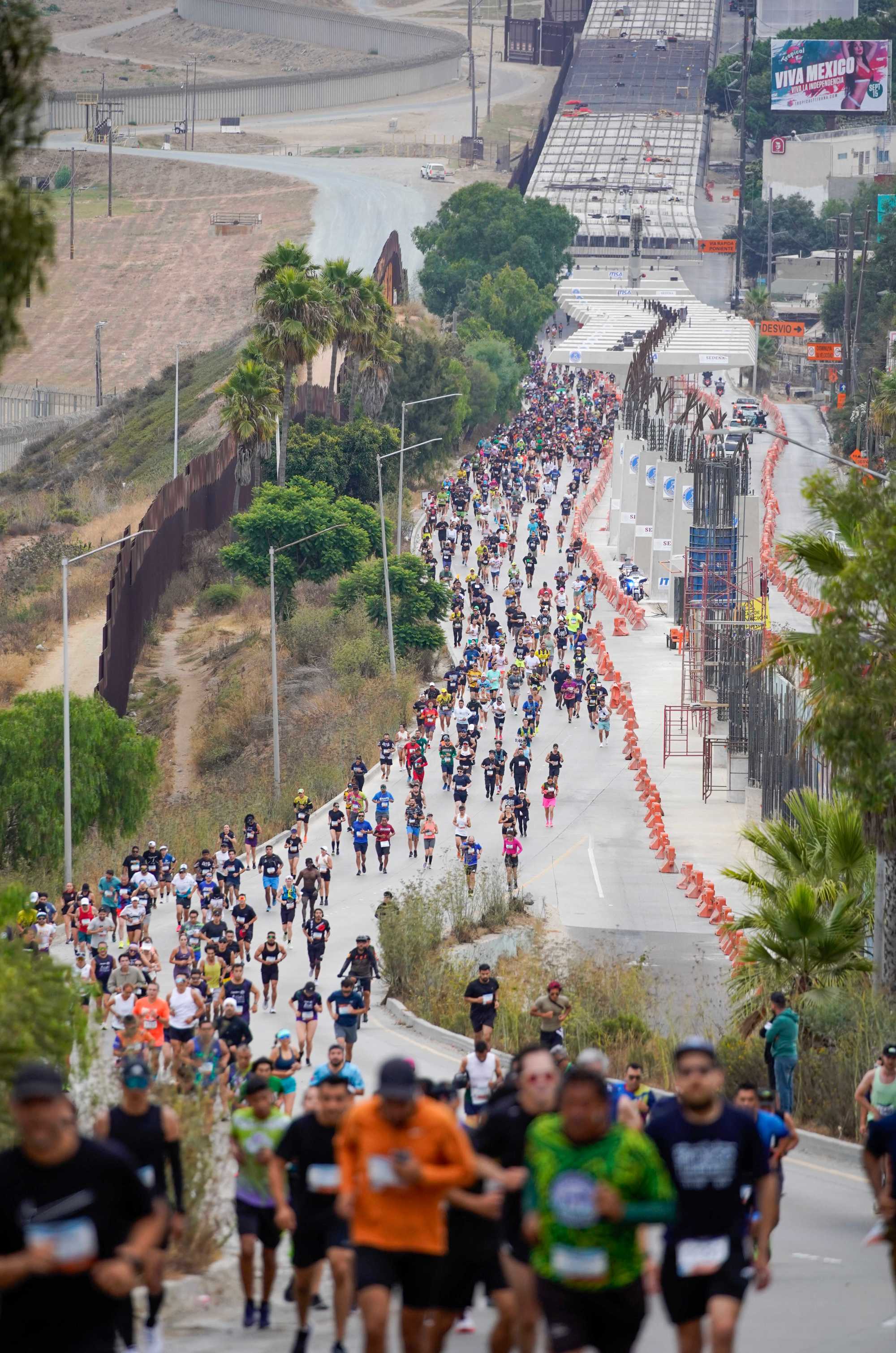 Runners compete in the Binational Race, from Las Americas Premium Outlets in San Ysidro to Playas de Tijuana. Runners on the Via International hill along the US/Mexico Border in Colonia Soler on Sunday, Sept. 15, 2024 in Tijuana, Baja California. (Alejandro Tamayo / The San Diego Union-Tribune)