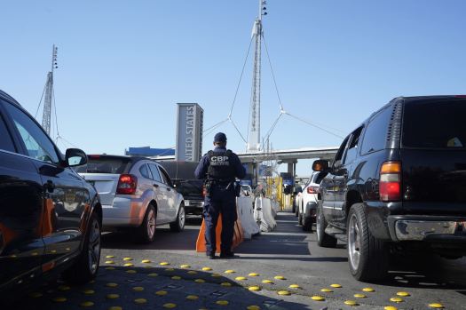 A U.S. Customs and Border Protection officer looks over vehicles. (Alejandro Tamayo / U-T file)
