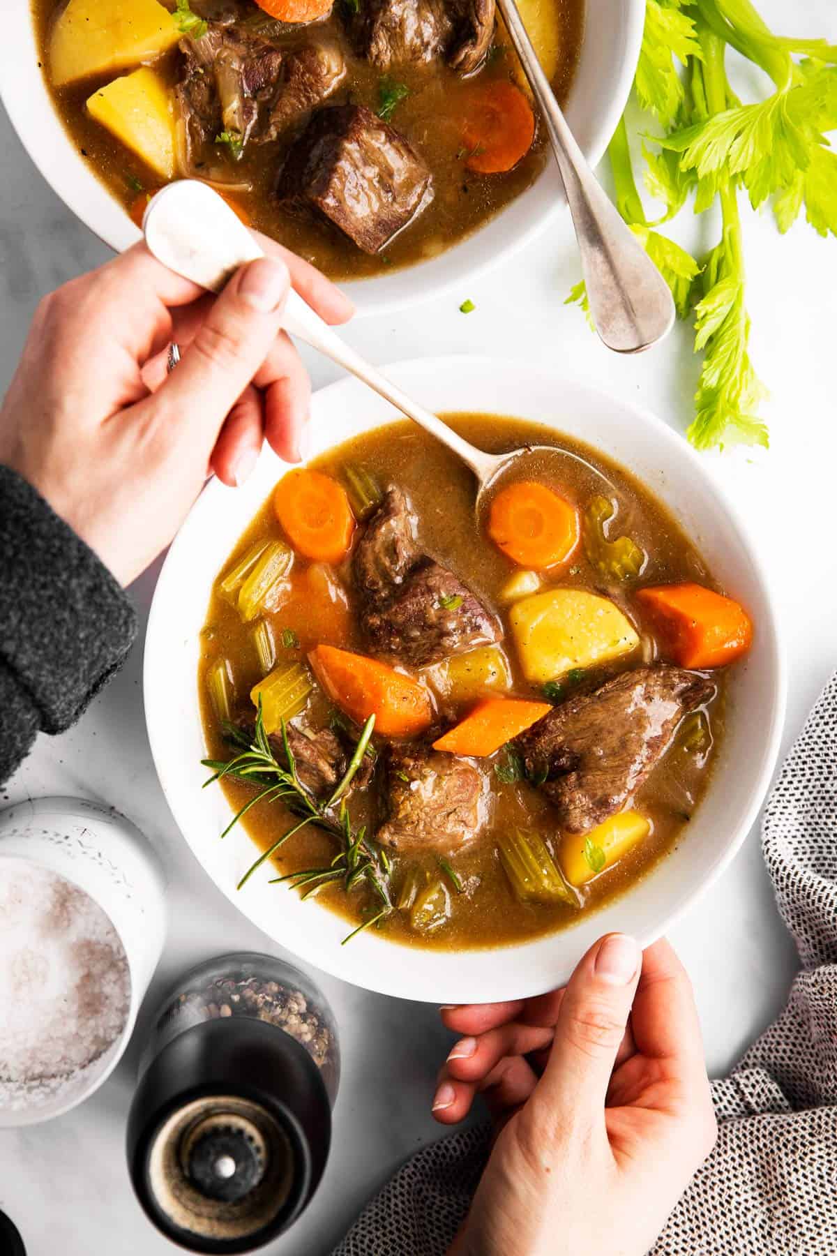 woman dunking a spoon into a bowl of beef stew