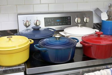 a variety of dutch ovens on a countertop and stove