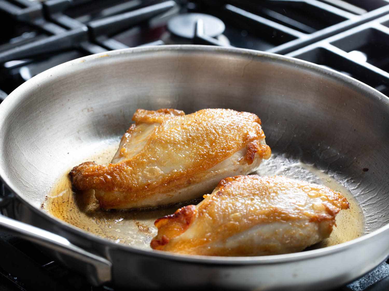 Searing chicken breasts in a skillet, showing even golden color on the skin