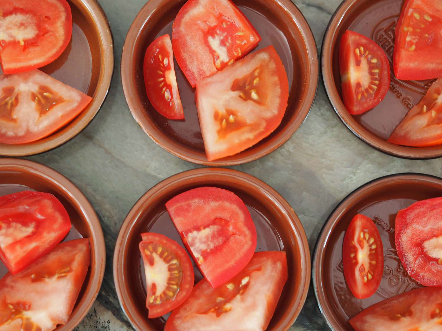 Pieces of tomato divided into various bowls for tasting.