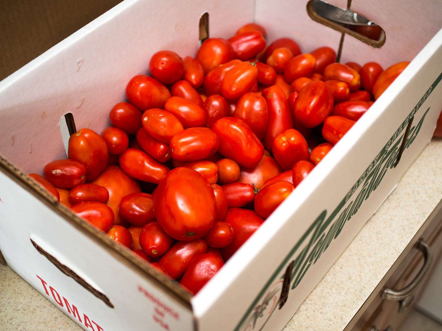 A cardboard carton of plum tomatoes.