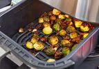 a closeup look at crispy Brussels sprouts in an air fryer basket