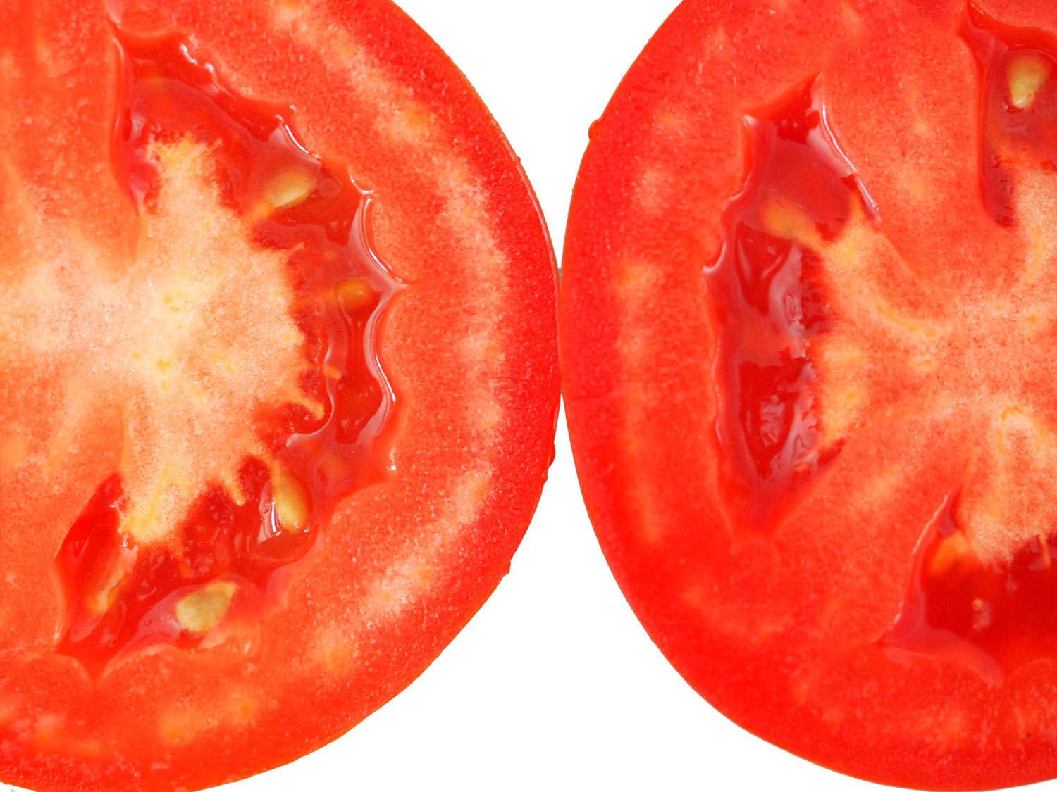 A close up look at two cut plum tomatoes so you can see inside. 