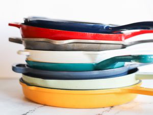 a stack of enameled cast iron skillets in multiple colors