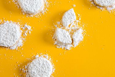 Powdered sugar-covered lemon meltaway cookies against a yellow background