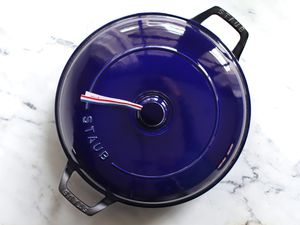 A blue Staub Cast Iron Braiser on a marble surface.