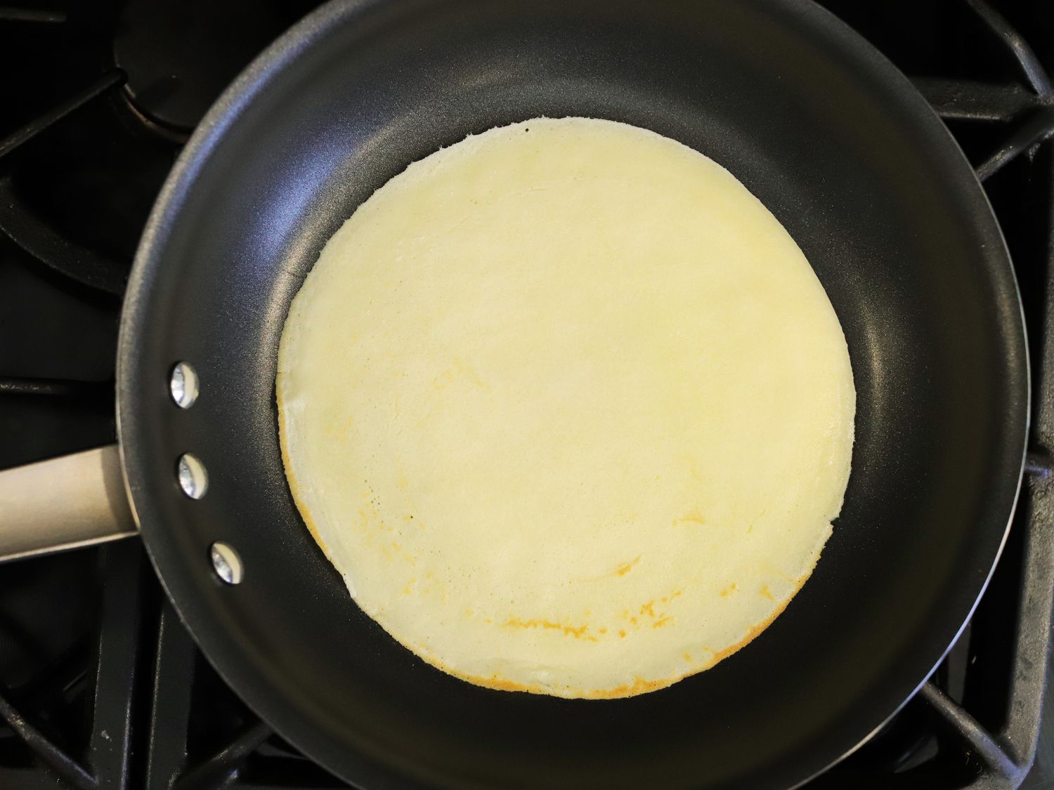 a closeup look at a cooked crepe in a nonstick skillet