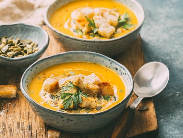 Two bowls of warm pumpkin soup with croutons and spices. Autumn food.