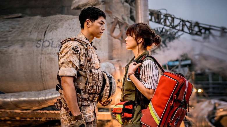 Mo-yeon (Song Hye-kyo) faces Si-jin (Song Joong-ki) in a war zone in Descendants of the Sun