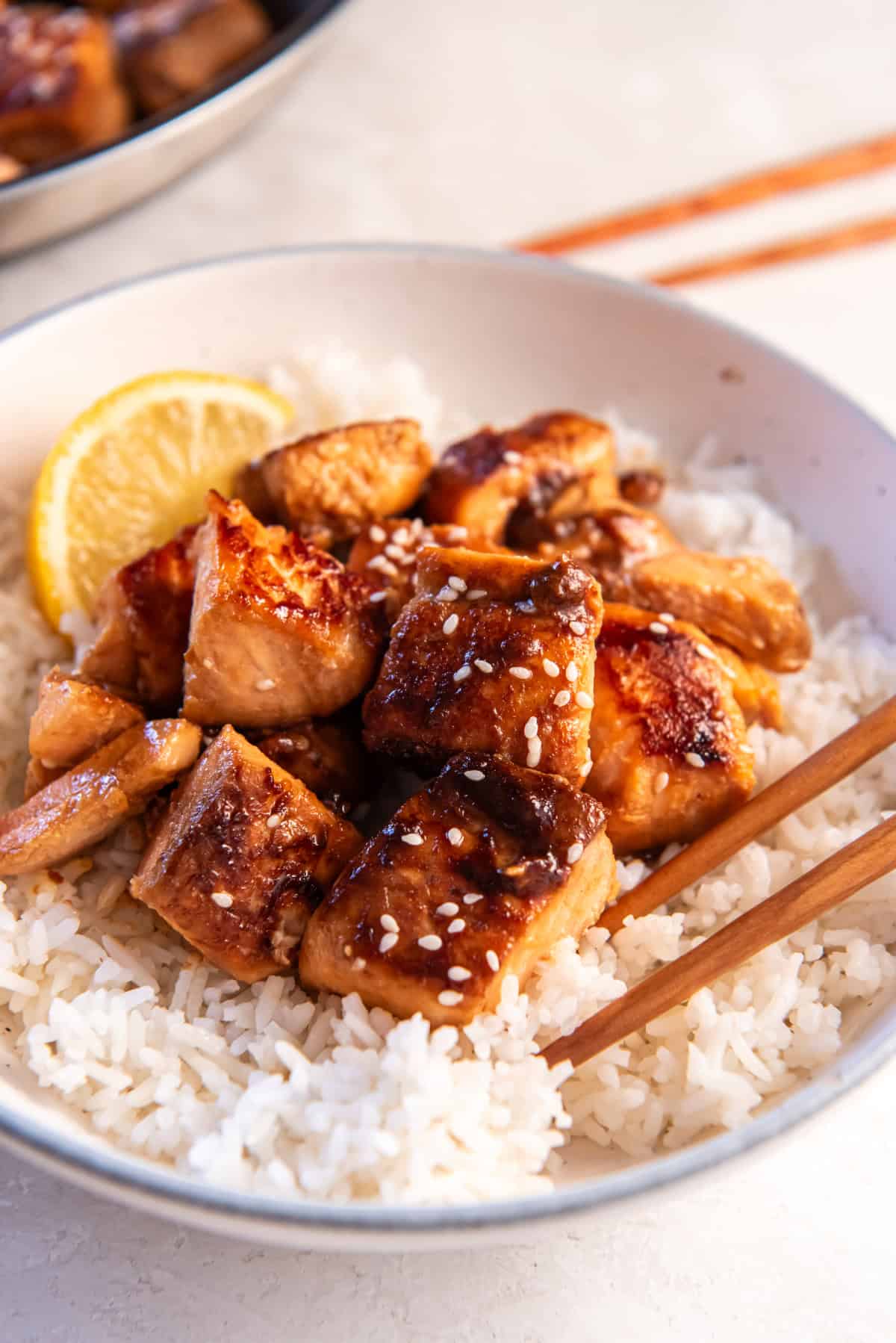 A plate of honey garlic salmon bites sitting on a bed of rice.