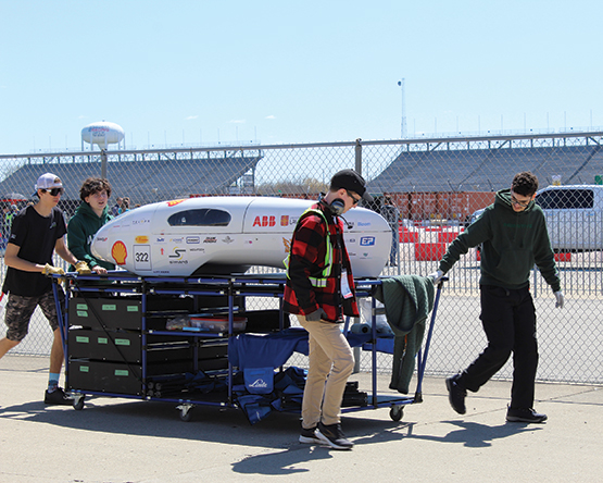 Students from the Alérion supermileage team with Université Laval in Canada haul their prototype BEV to the test track for inspection.