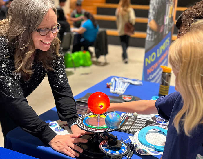 white woman assisting young female with science experiment