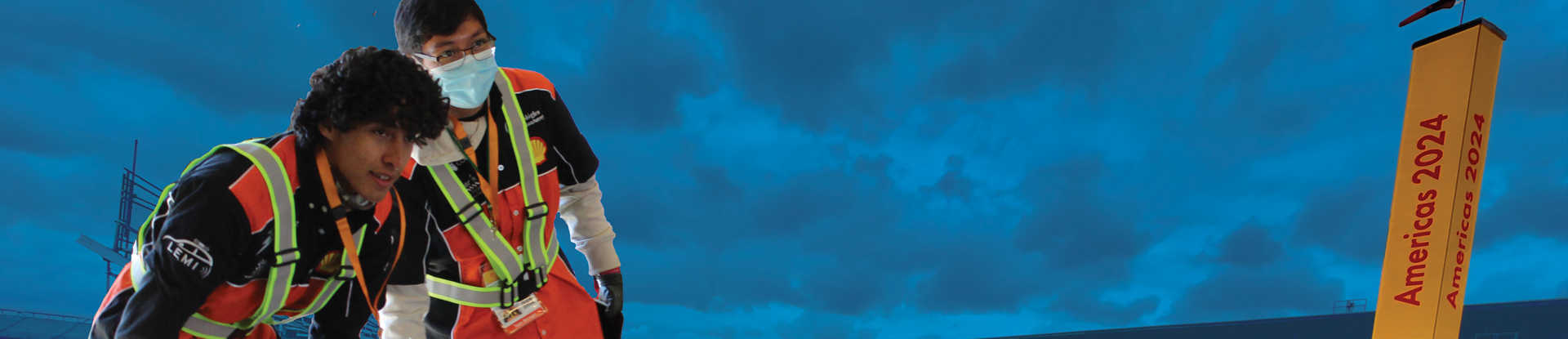 Two boys with safety vests on look into the distance against a blue background