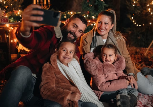 Two kids with parents taking a group selfie during the holiday season