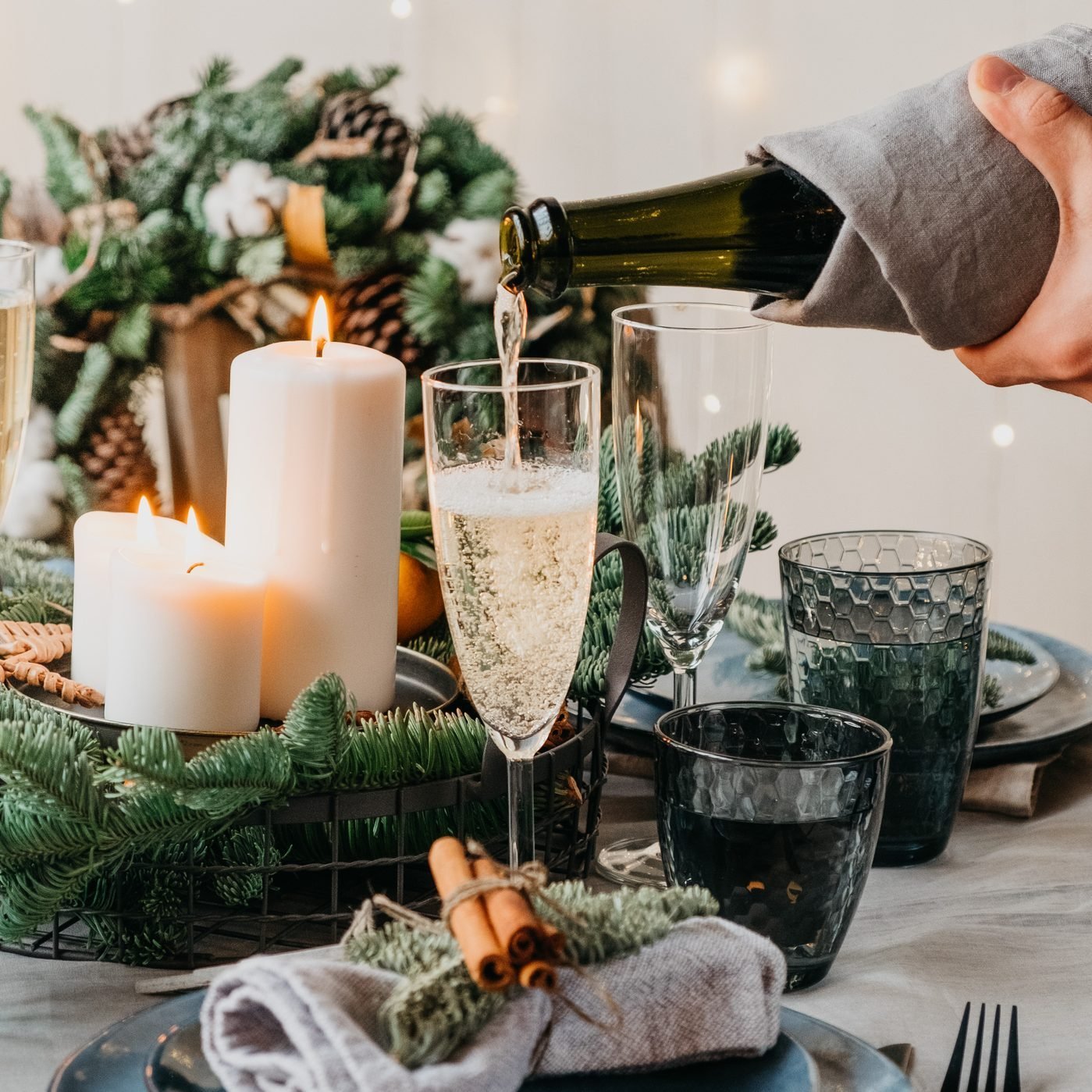 a hand pouring champagne into a glass on a table decorated for a new year's celebration