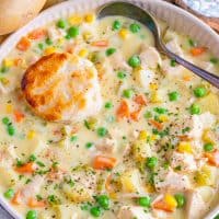 Square close up overhead image of Chicken Pot Pie Soup in bowl with biscuit and spoon.