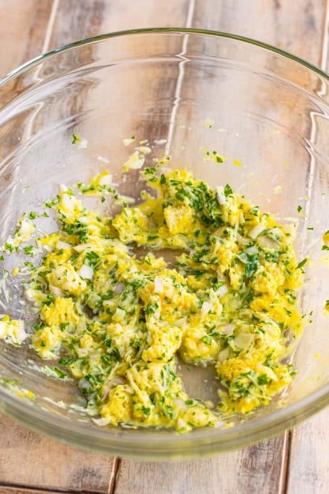 A large mixing bowl with torn white bread, milk, parmesan cheese, egg, shallot, lemon zest, salt, and parsley.