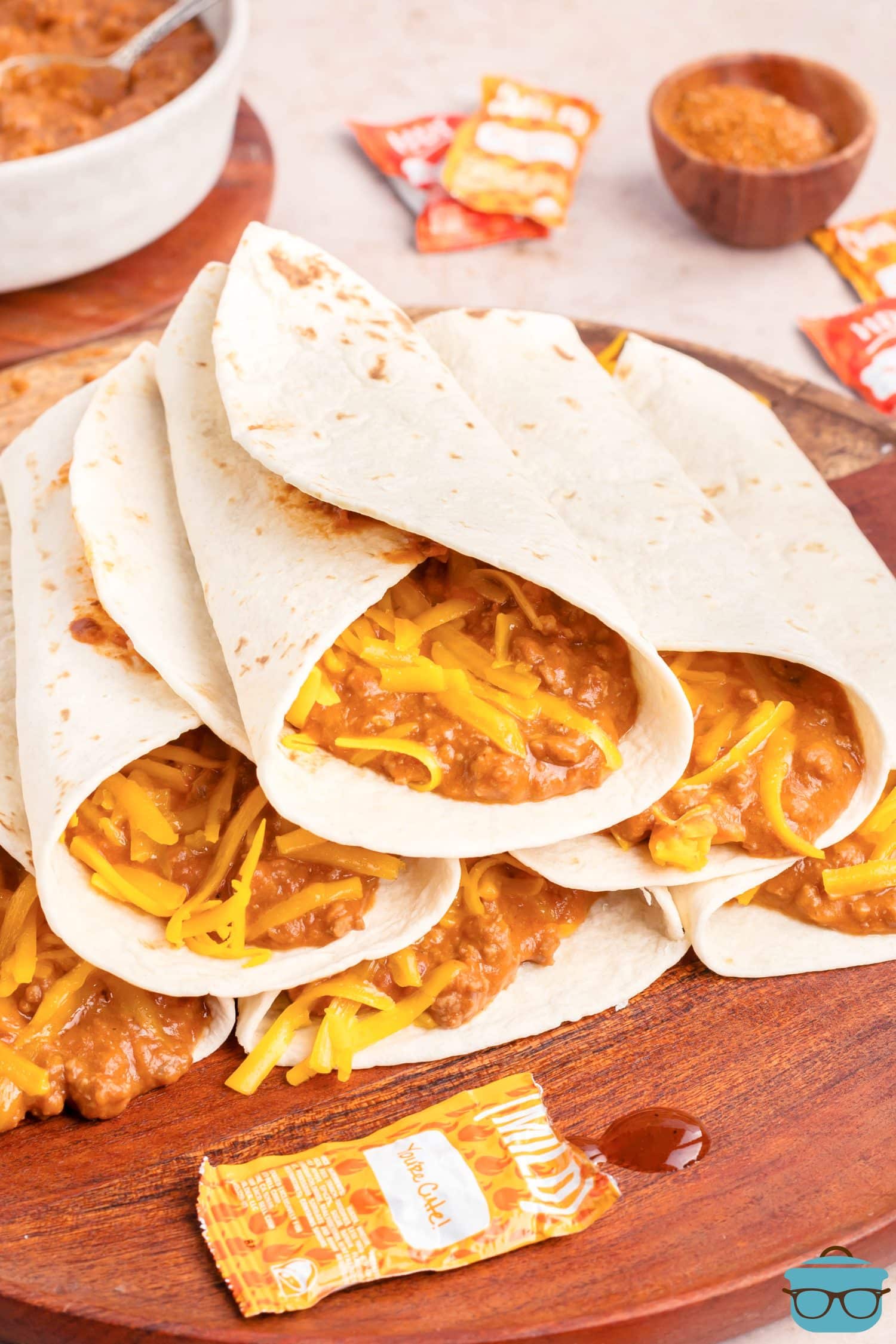 A few Chili Cheese Burritos on a chopping board.