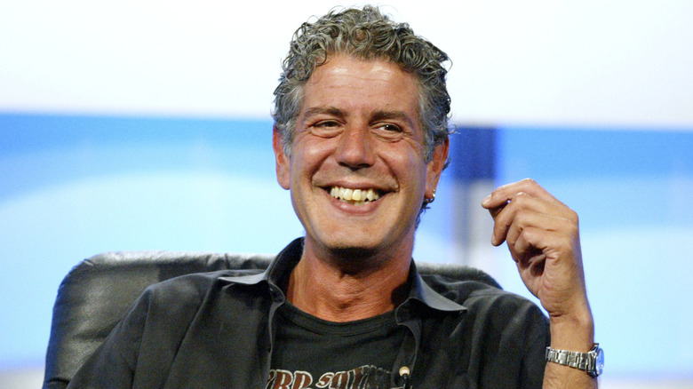 Anthony Bourdain smiling while sitting in a chair