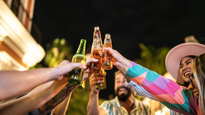 a group of friends in Mexico cheering with bottles of beer