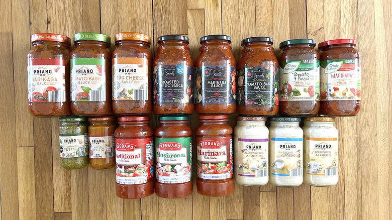 Various Aldi pasta sauce jars on wooden counter.