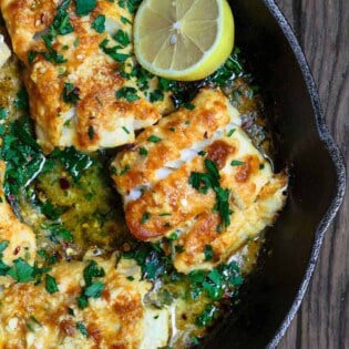 Baked cod recipe with lemon and garlic, served on a cast-iron skillet